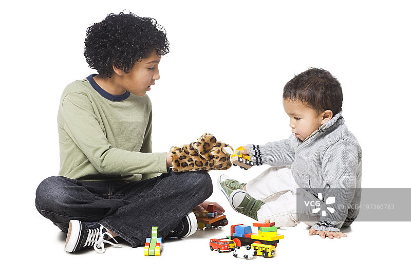 兄弟俩(18-23个月)(8-9个月)在白色的背景下玩玩具图片素材