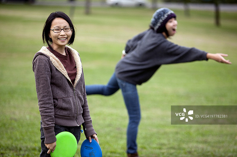 两位年轻的亚裔美国女子在马里兰州的巴尔的摩玩飞碟高尔夫。图片素材
