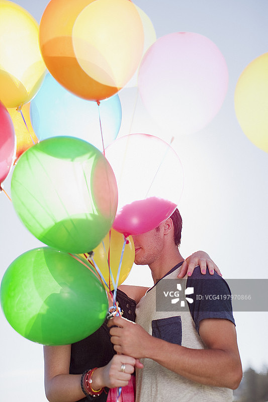 情侣在气球后面接吻图片素材