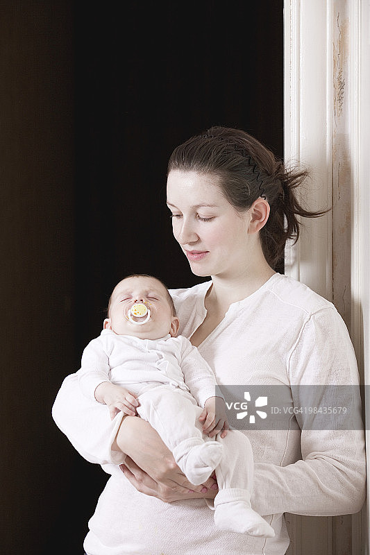 年轻母亲抱着熟睡的女儿的肖像图片素材