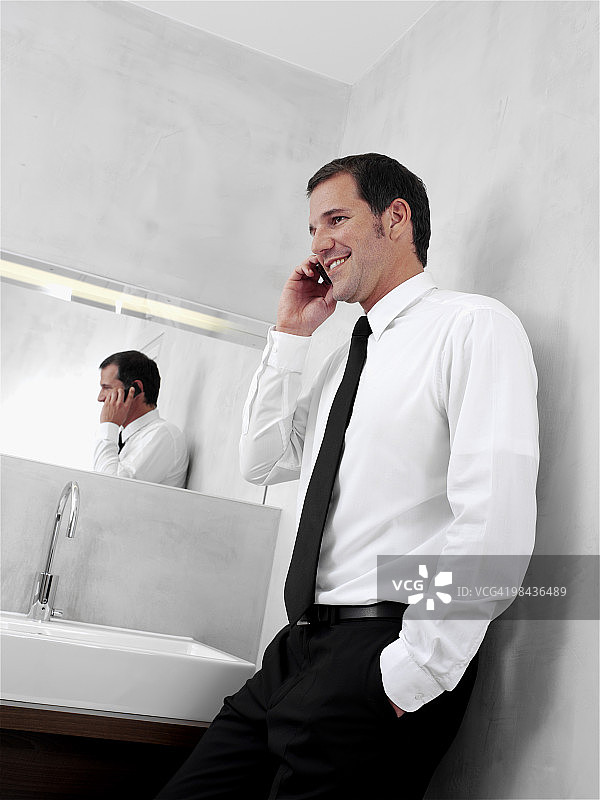 一幅年轻商人在浴室镜子前用手机聊天的肖像图片素材