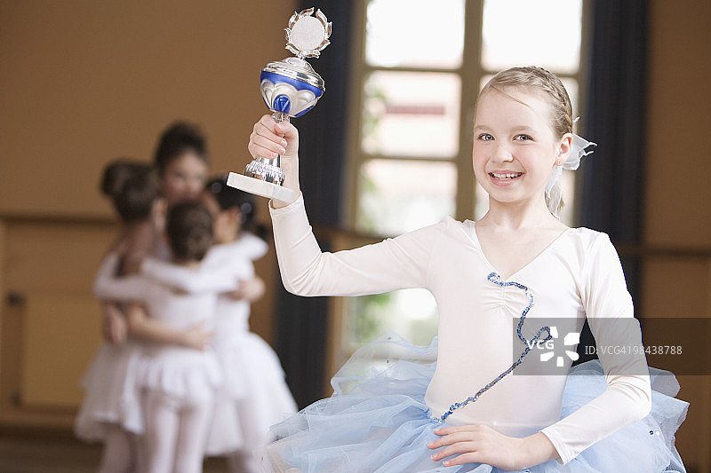 年轻的芭蕾舞演员拿着奖杯站在小组前面图片素材