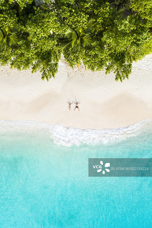 一对夫妇躺在热带海滩上的鸟瞰图图片素材