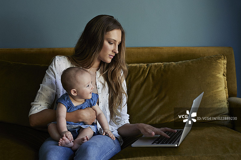 母亲和新生婴儿坐在一起，手提电脑图片素材