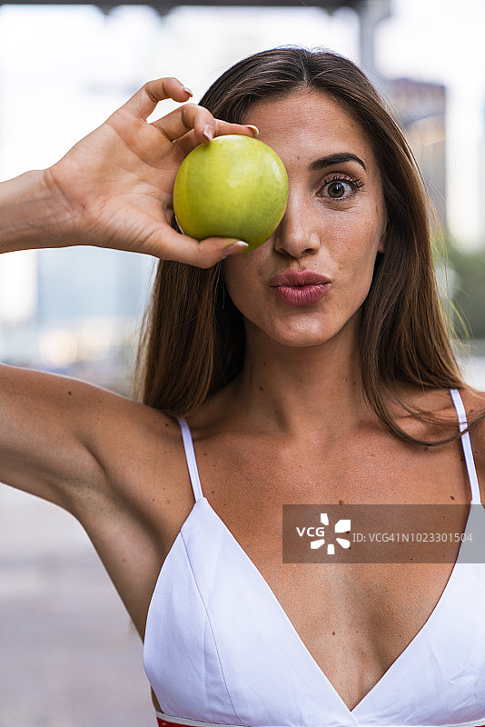 有吸引力的年轻女人的肖像穿着运动胸罩拿着一个苹果图片素材