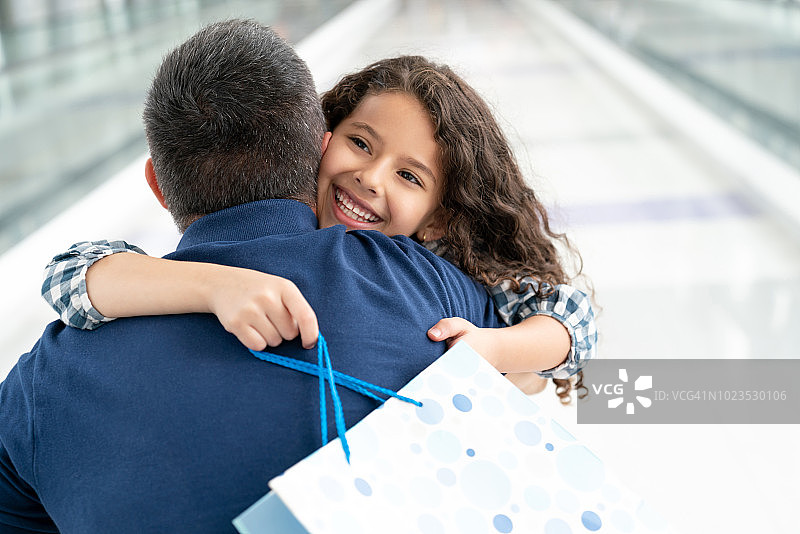 可爱的小女孩在机场拥抱她的爸爸，看起来很兴奋图片素材