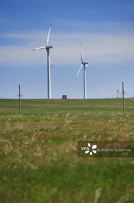 风力涡轮机在一个草地上耕作图片素材