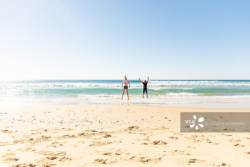 两个孩子在澳大利亚昆士兰黄金海岸海滩的沙子和水里玩耍图片素材
