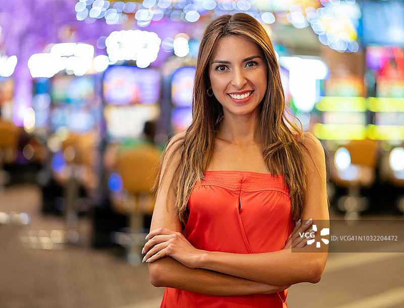 美丽的拉丁美洲女人的肖像与双臂交叉在赌场看着镜头微笑图片素材