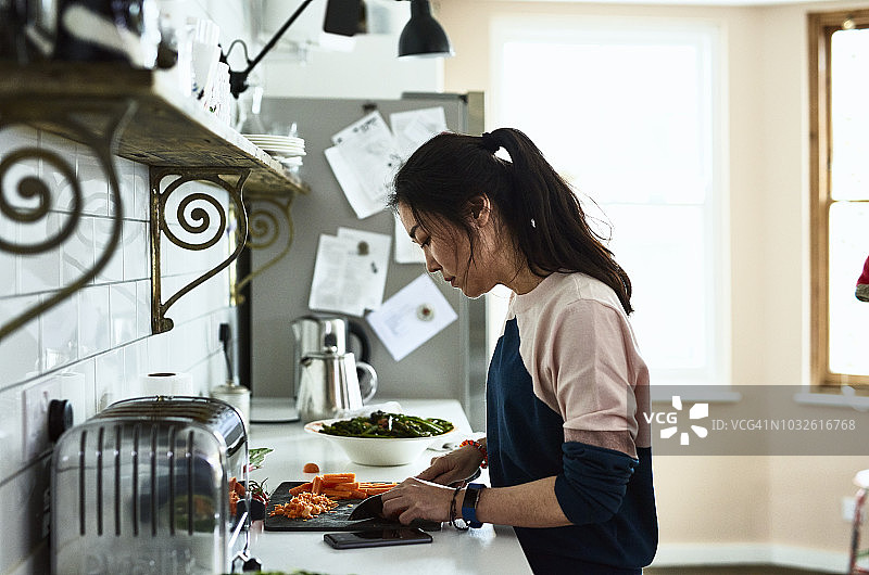 中年韩国妇女在厨房柜台上切菜图片素材
