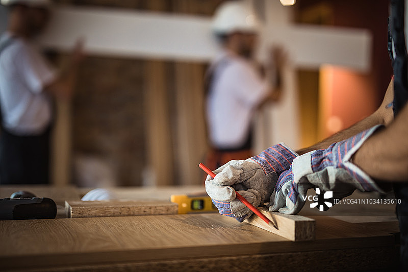 在家庭装修过程中，建筑工人在木板上绘制测量图的特写。图片素材