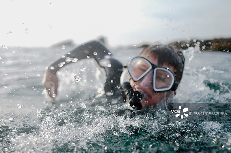 戴着通气管和面罩在海里游泳的男孩，奥兰治县，美国图片素材