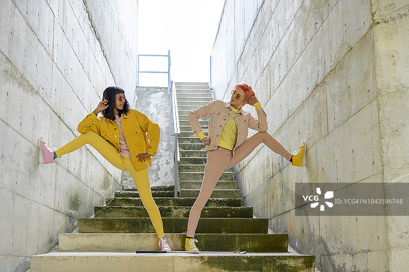 两个穿着黄色和粉色牛仔裤的朋友在台阶上摆姿势图片素材