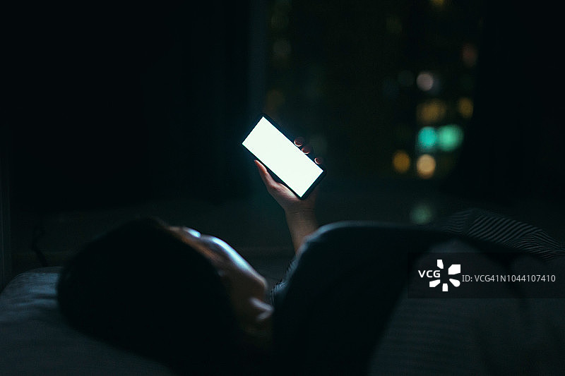 半夜躺在床上看手机短信的女人图片素材