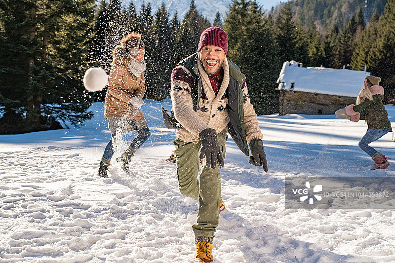 一个人和他的朋友一起玩的时候把雪球扔向空中图片素材