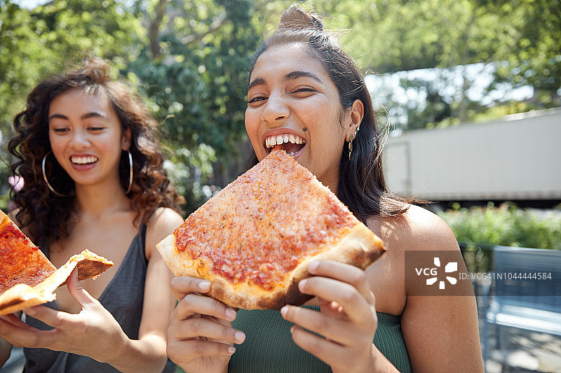 年轻女性在城里吃披萨图片素材