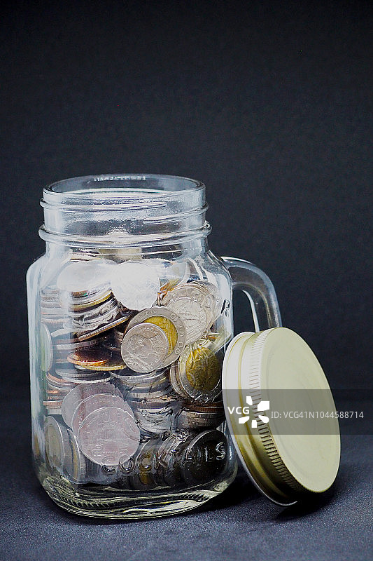 存钱罐里装满硬币，孤立在黑色背景上图片素材