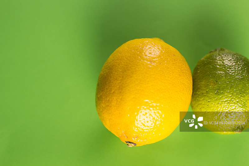 新鲜的柠檬和酸橙在绿色柔和的背景上。关闭了。图片素材