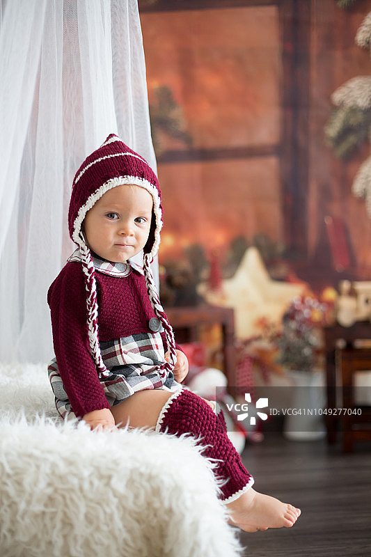 时髦的蹒跚学步的小男孩，在圣诞装饰周围玩耍图片素材