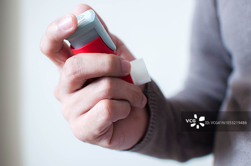一个年轻人拿着一个红色的哮喘吸入器图片素材