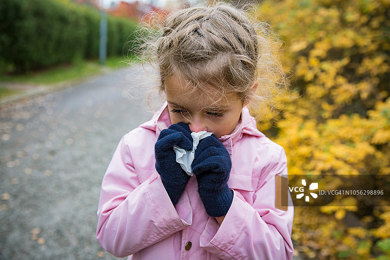 生病的小女孩得了感冒和流感站在外面。图片素材