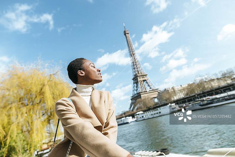 法国，巴黎，在塞纳河上闭着眼睛的女人，背景是埃菲尔铁塔图片素材