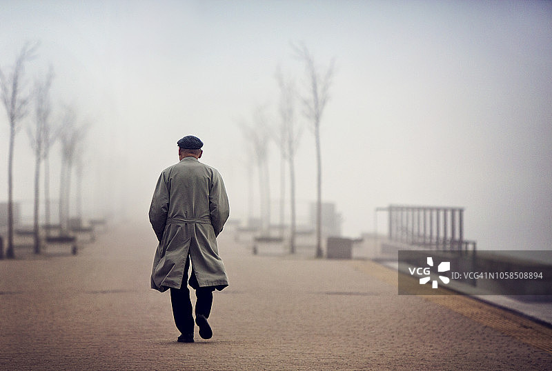 一个老人走在空旷雾蒙蒙的路上图片素材