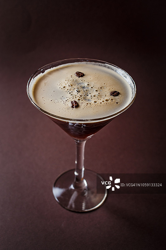一杯浓咖啡马提尼，咖啡豆和伏特加在优雅的深棕色背景图片素材