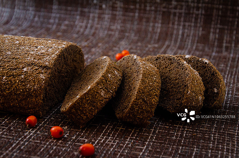 沙棘黑麦面包一种面包片，在传统的背景上撒有沙棘浆果图片素材