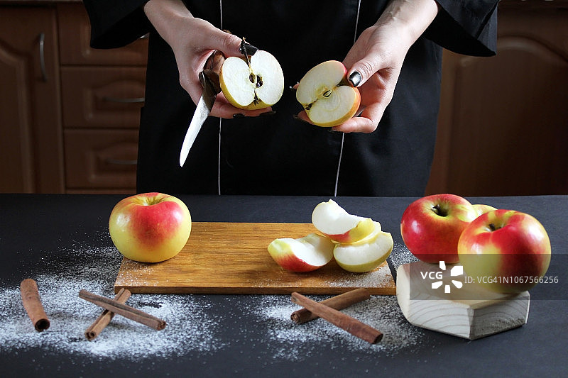 厨师把苹果切成小块以便烘烤。黑色的桌子上放着成熟的苹果、小刀、糖粉和肉桂。苹果玫瑰的烹饪过程。第二步是把苹果切成片图片素材