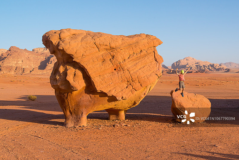 男孩从约旦瓦迪拉姆沙漠的一块岩石上跳下来图片素材