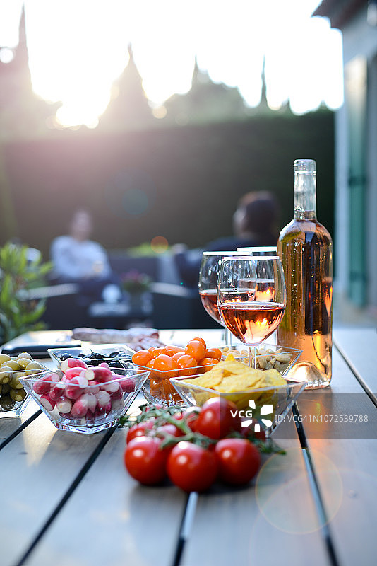 假日夏季早午餐派对桌子户外在房子后院的开胃菜，一杯玫瑰葡萄酒，新鲜饮料和有机蔬菜。图片素材