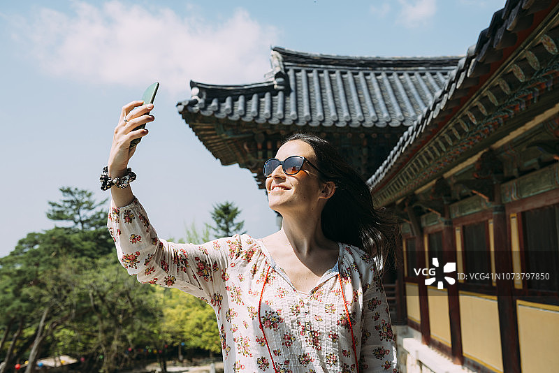 韩国庆州，一名快乐的女子在八宫寺用手机自拍图片素材
