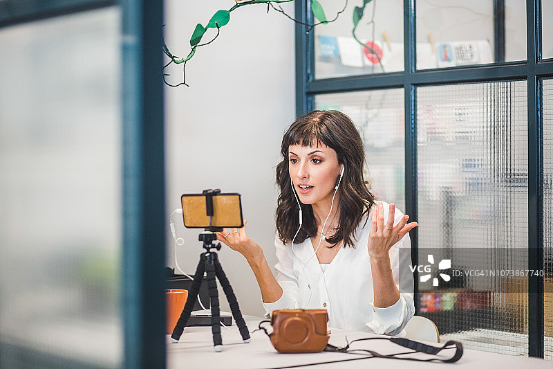 创意女企业家在办公桌边通过移动电话参加视频会议图片素材