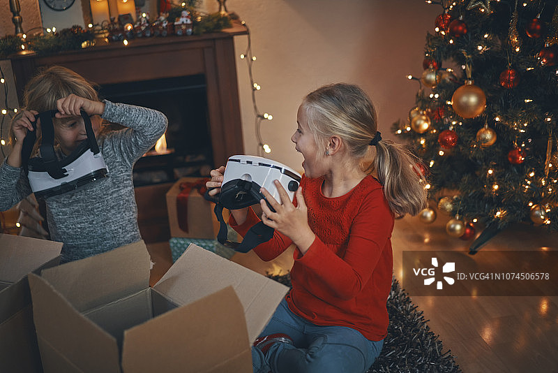 在舒适的圣诞氛围中，孩子们在客厅玩VR眼镜图片素材