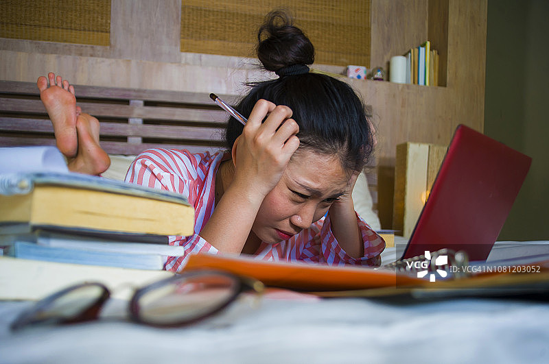年轻绝望和疲惫的亚洲韩国大学生女孩感到不堪重负和压力准备考试学习的笔记本电脑在压力过度工作和绝望在床上图片素材