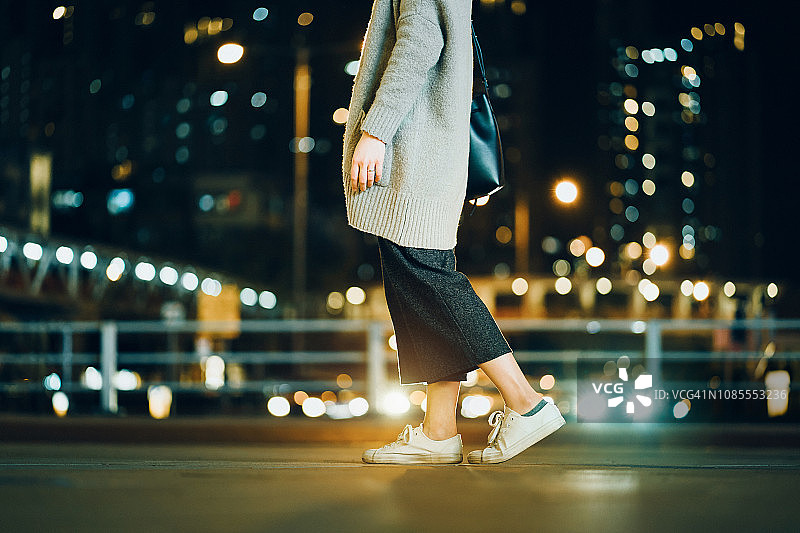 裁剪图像的女人走在灯光照亮的城市晚上图片素材