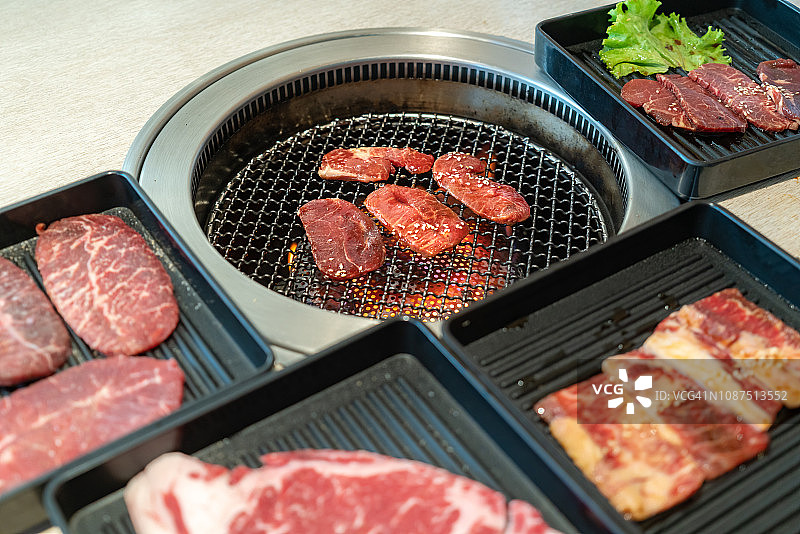 生牛肉片用于烧烤或日式烧肉，在日本的炉子上用木炭烧烤。图片素材