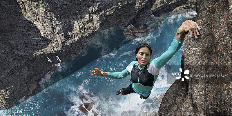 自由攀登者一只手悬挂在海崖岩壁上图片素材
