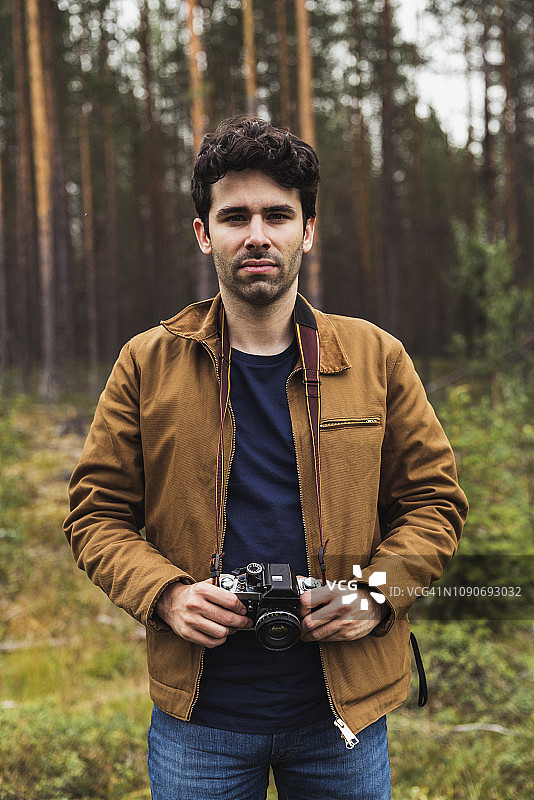 芬兰，拉普兰，一个年轻人拿着相机在乡村风景中的肖像图片素材