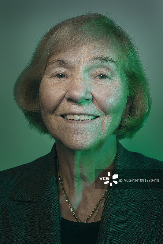 肖像年长，成熟的商业妇女在绿色的光微笑图片素材