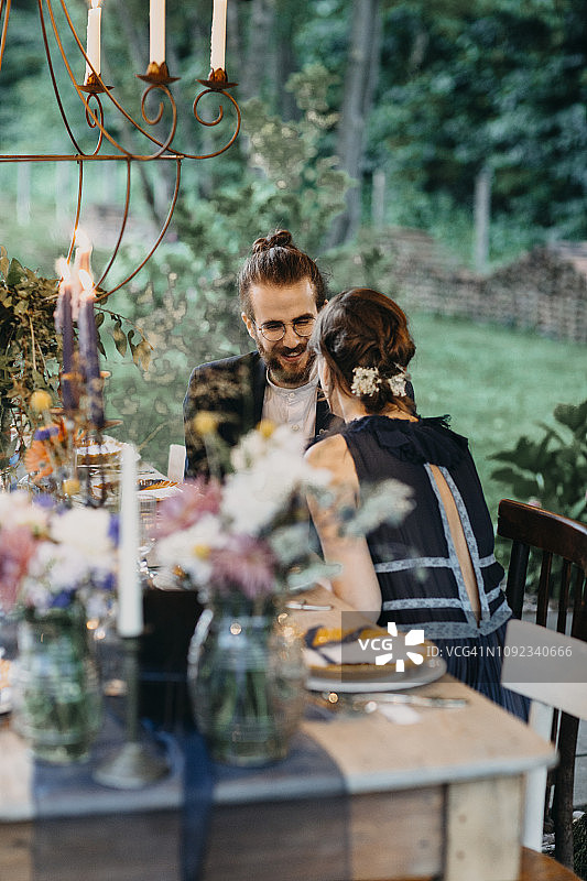 快乐的新娘和新郎坐在节日铺好的桌子外面图片素材
