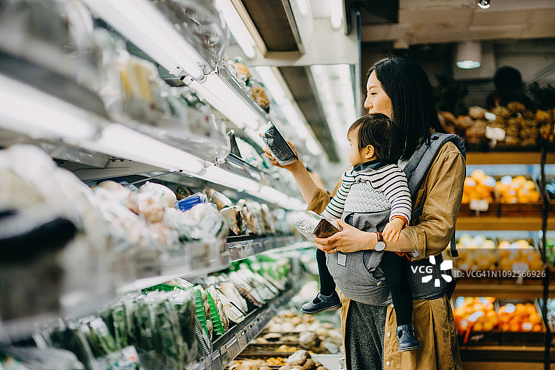 年轻的妈妈带着小女孩在超市买菜，买新鲜的有机蔬菜和水果图片素材
