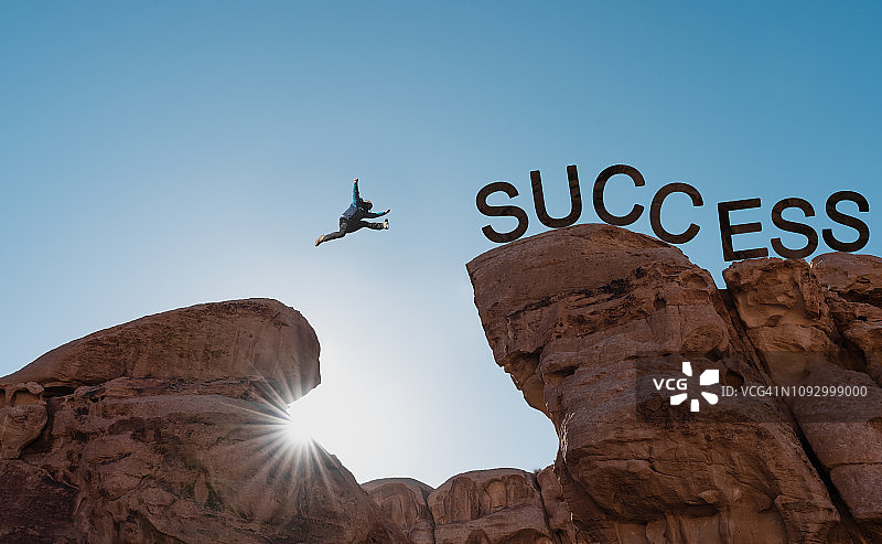 剪影一个人跳下悬崖走向成功。商业成功、挑战、成就和领导理念图片素材