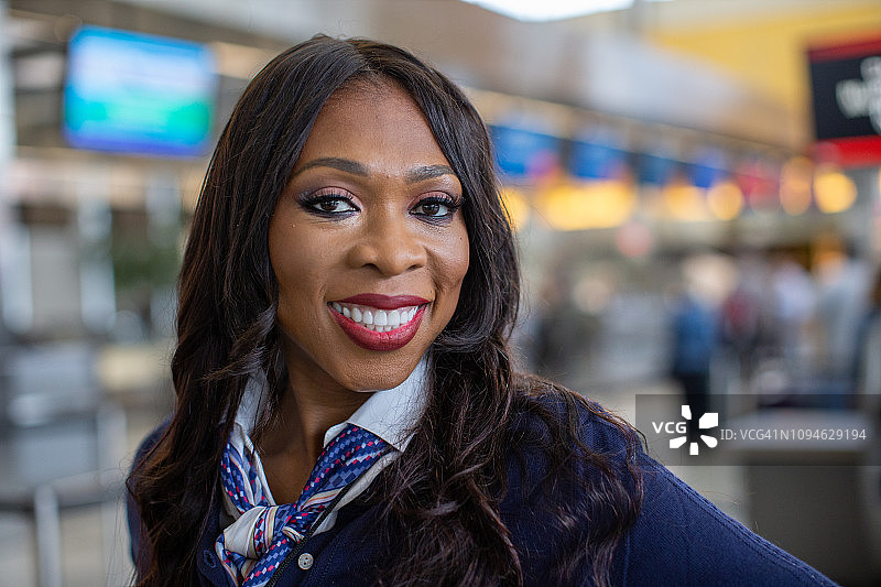 非裔美国空乘人员在机场大厅对着镜头微笑的肖像。图片素材