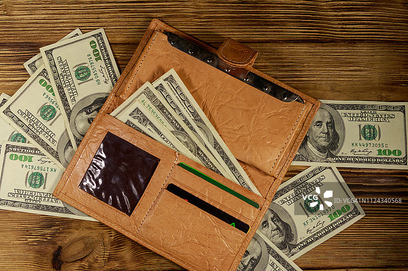 打开钱包和美元放在木桌上。俯视图图片素材