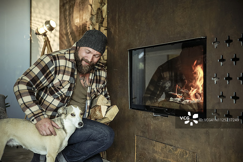 有胡子的男人和他的狗在家里的壁炉前图片素材