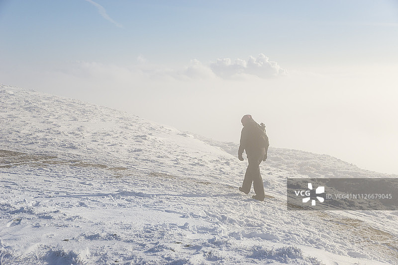 在极端冬季条件下在山上徒步旅行的人图片素材