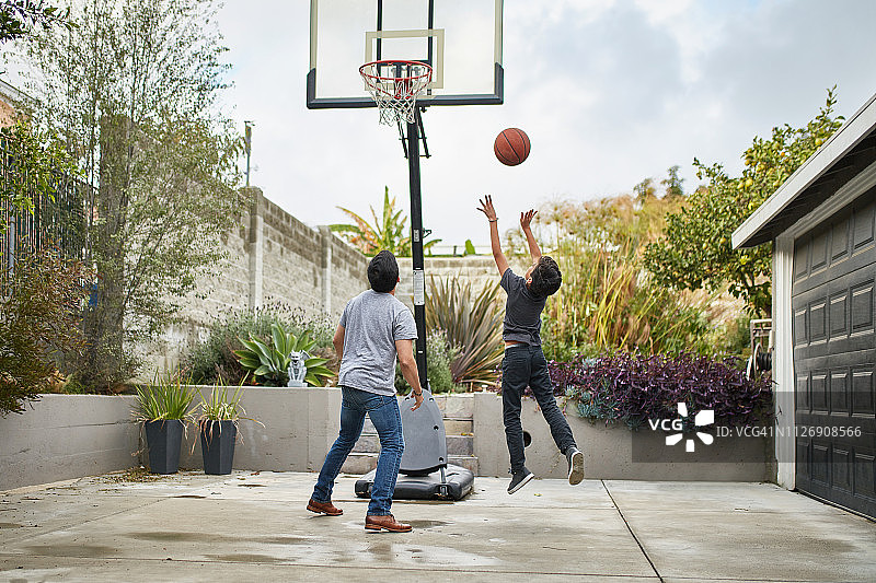父亲看着儿子在院子里打篮球图片素材