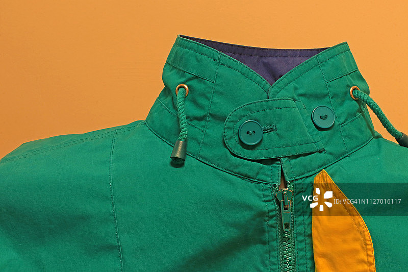 黄色背景下的绿色夹克，领口扣上，拉链和衬里图片素材